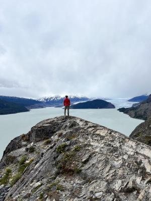 Ich auf einem Felsen in roter Jacke vor dem See und dem Grey Gletscher