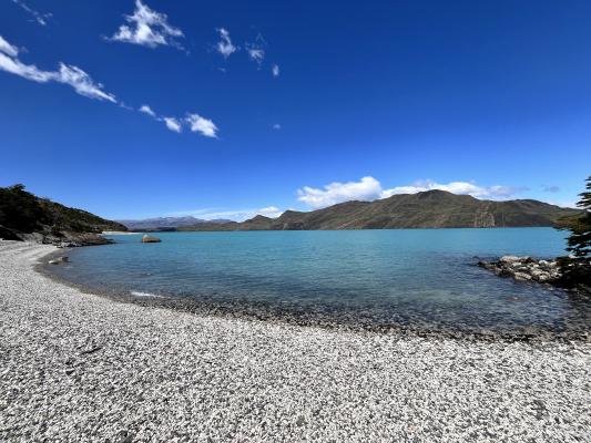 Azurblauer See mit schwarz-weißem Kieselstrand